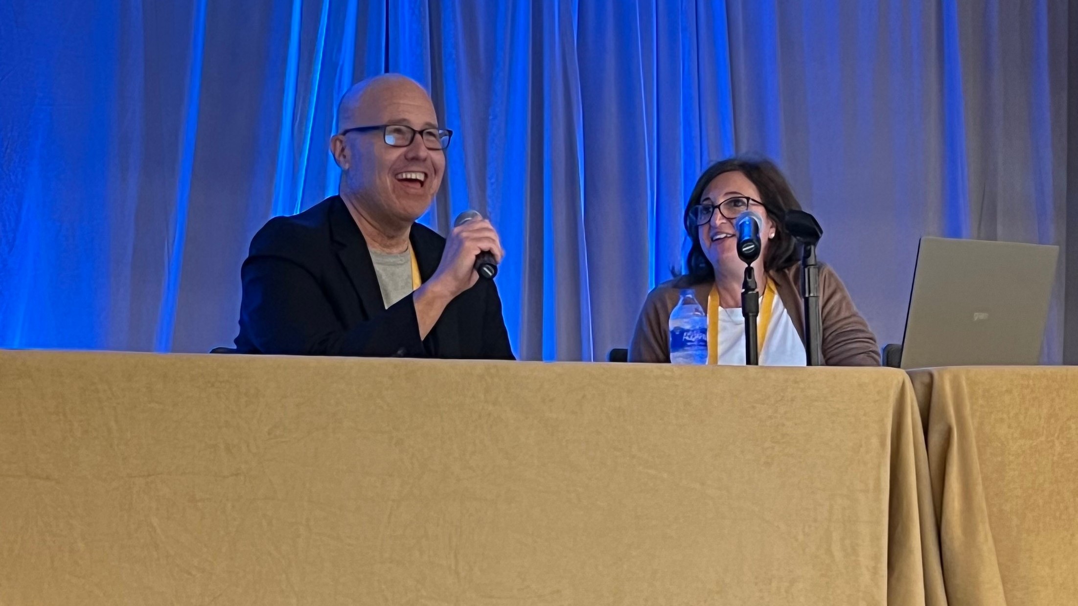 Bill and Ana_RISE Summit Bill Friedman and Ana Handshuh speaking together at a table with microphones at the RISE HEDIS 2022 conference